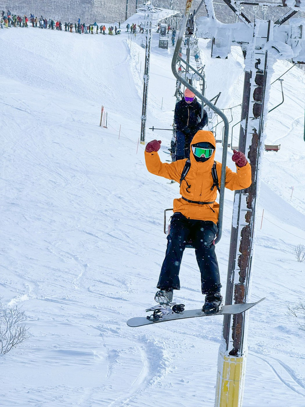 Snowboarder on a ski lift with a clean, snow-free board after using Slope-X